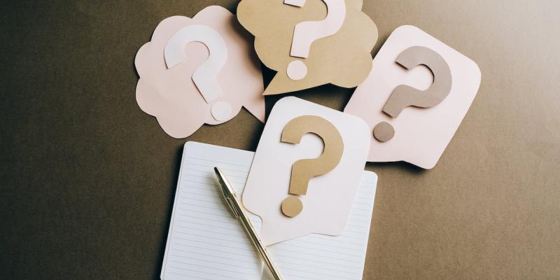 Get Answers to Some of the Most Common Home Buyer Questions Paper cut out question marks over a notepad and pen on a table